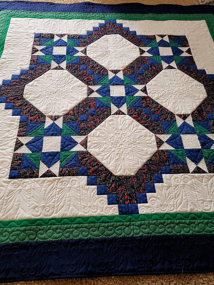 Janet H: I found the center of this top at a second hand store for $8.  Added three borders to make it larger and quilted it. 